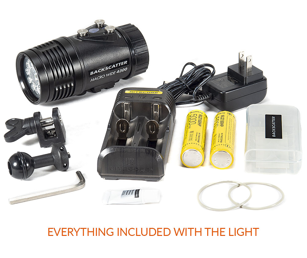 Backscatter Macro Wide 4300 Underwater Video Light kit with all included accessories: the light itself, dual rechargeable batteries, charger with power cable, mounting hardware, battery storage case, spare O-rings, an Allen wrench, and lubricant. This complete setup provides everything needed for underwater photography right out of the box.