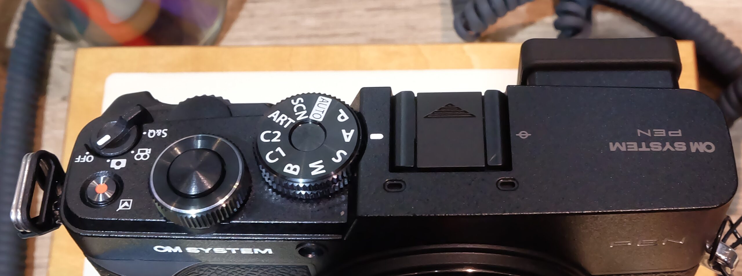 Detailed top view of OM SYSTEM PEN 2026 showing PASM dial and command controls